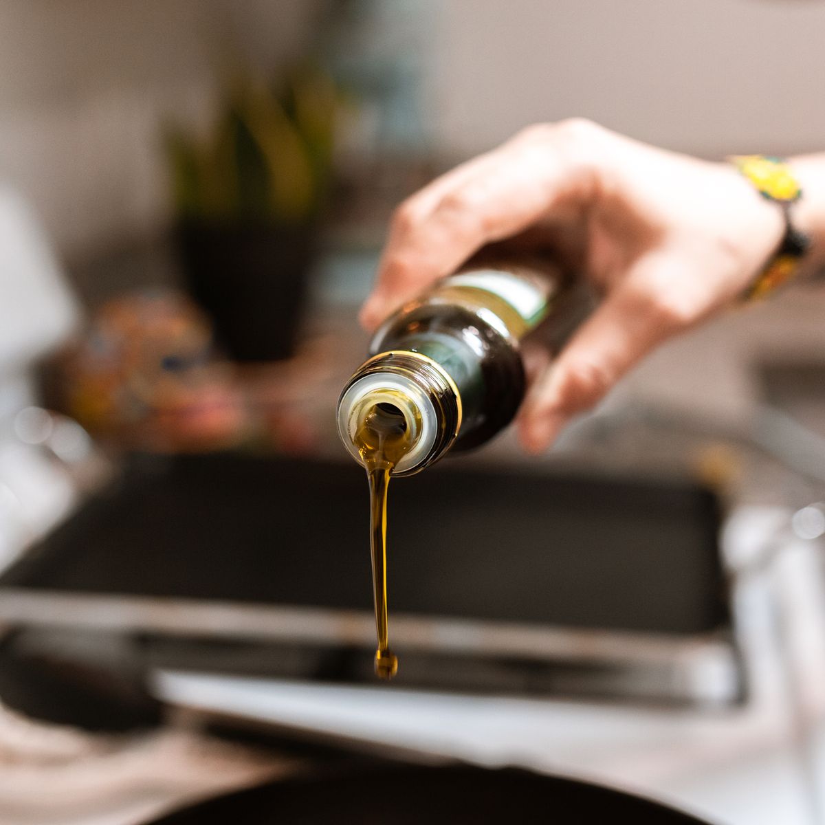 A hand pouring oil from a glass bottle
