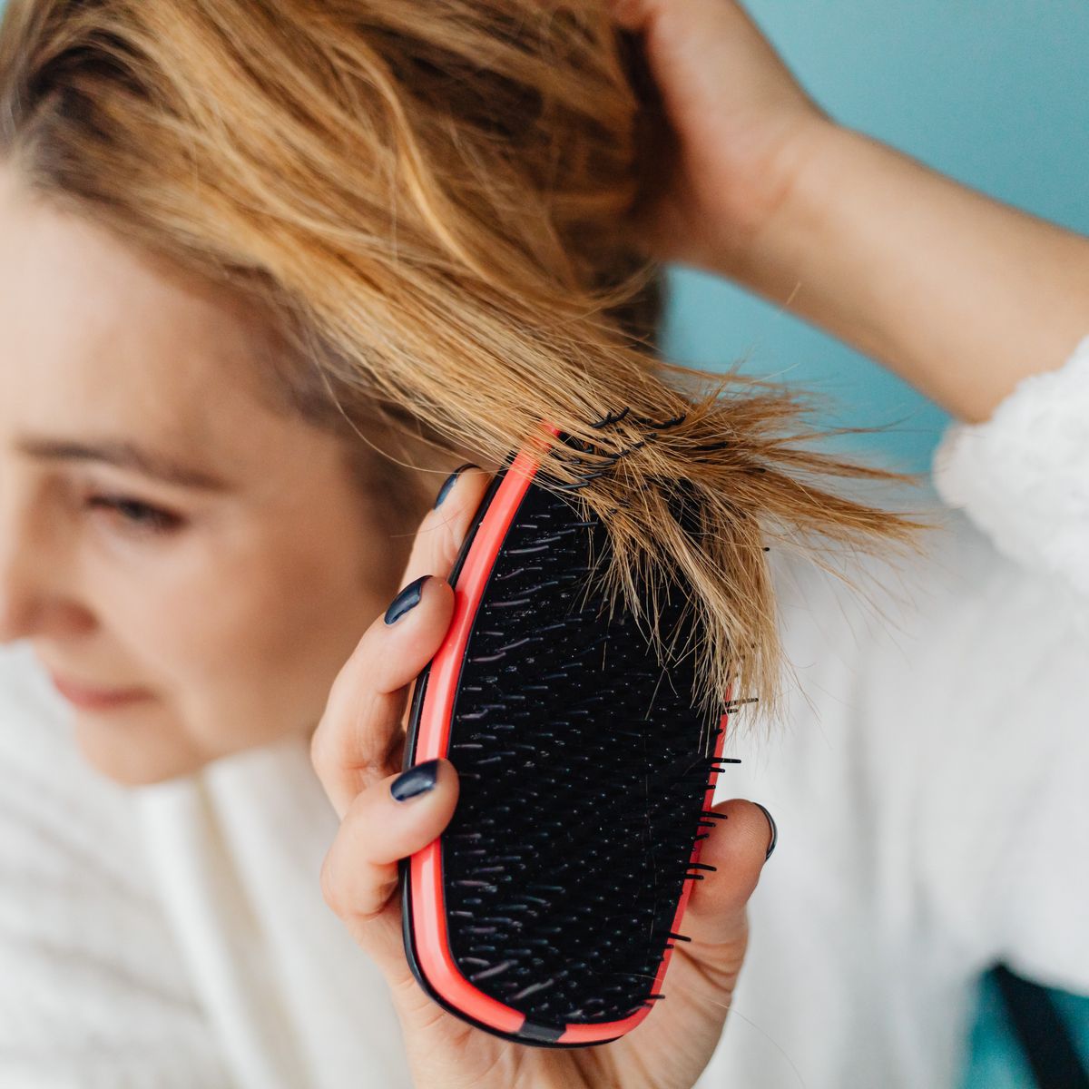 Close-up of a woman parting her hair to examine her scalp
