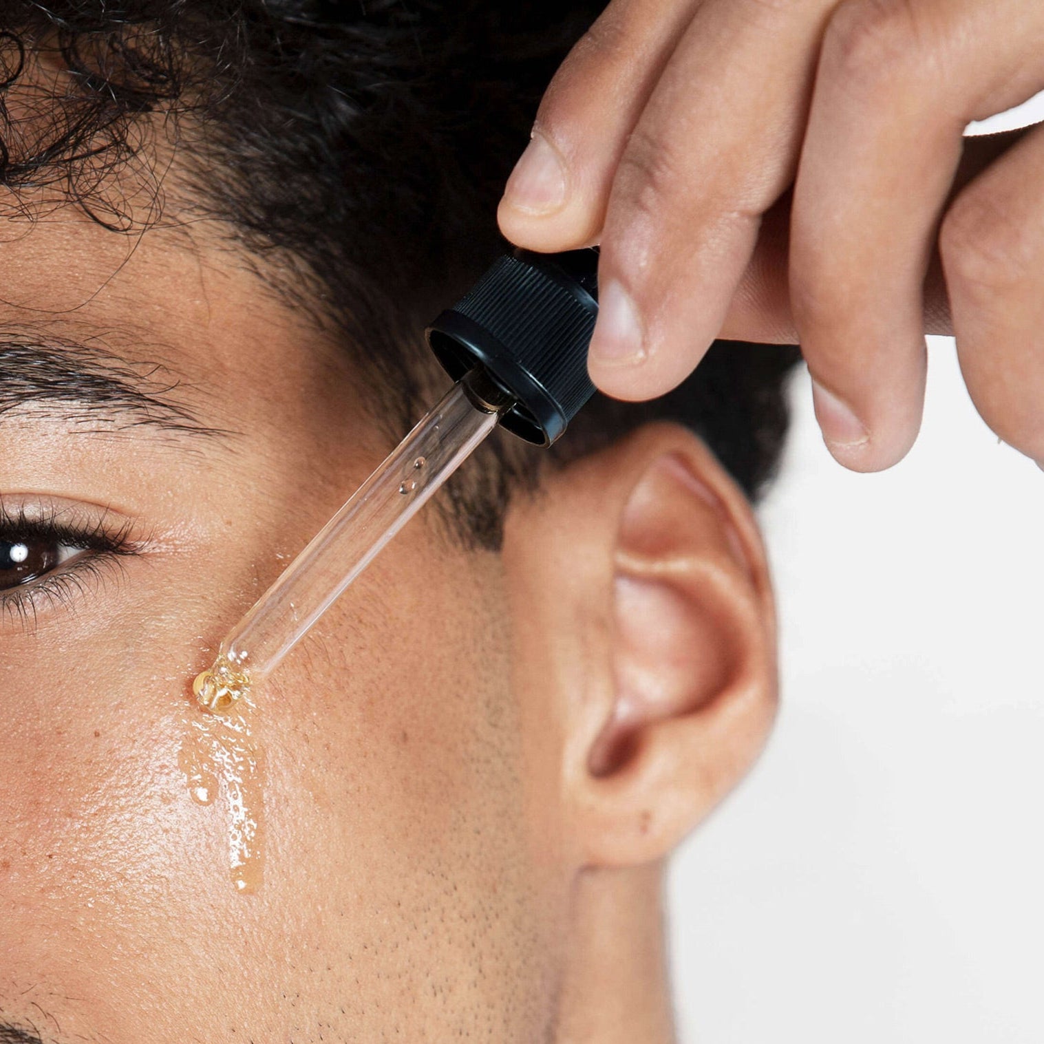 Man applying a dropper of octaskin serum product to his face.
