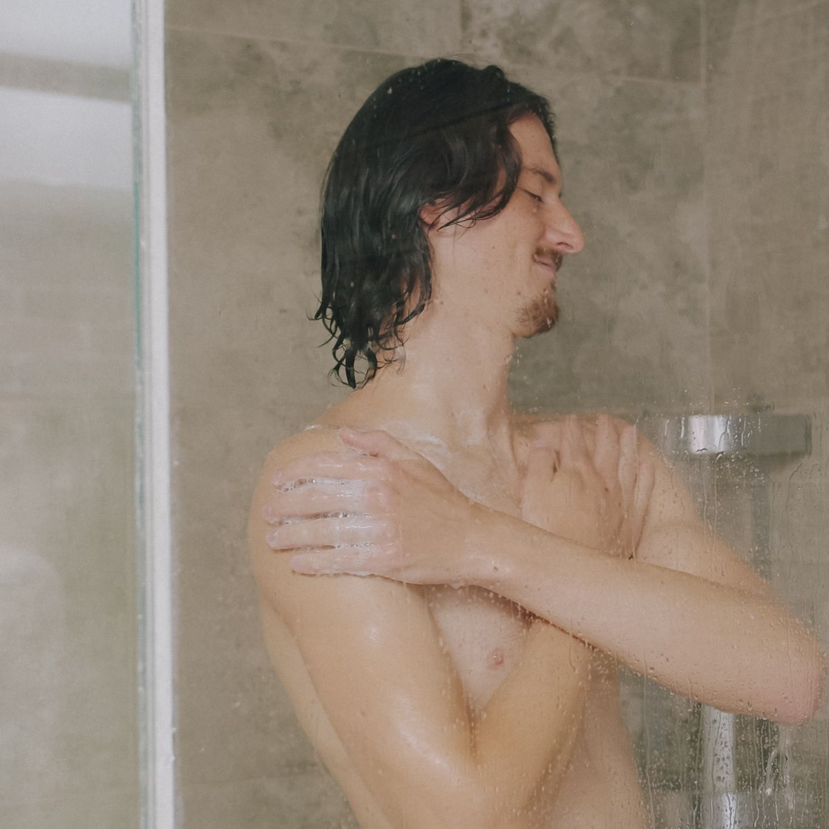 A man showering, water running over his shoulder