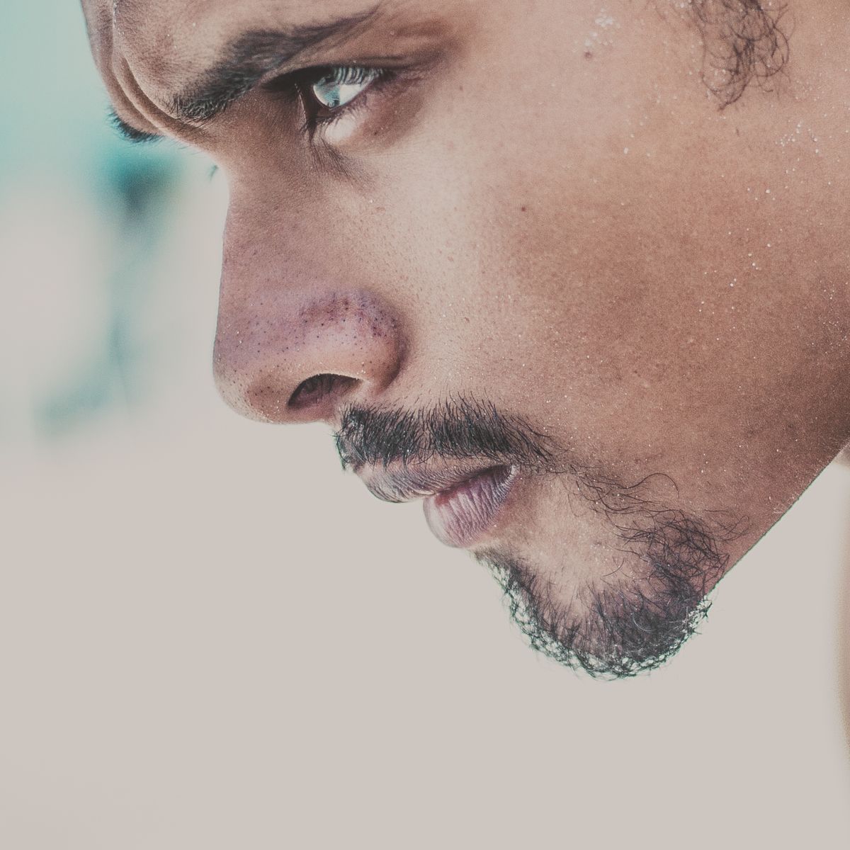 Man in his late thirties gently checking the skin just behind his ear with two fingers